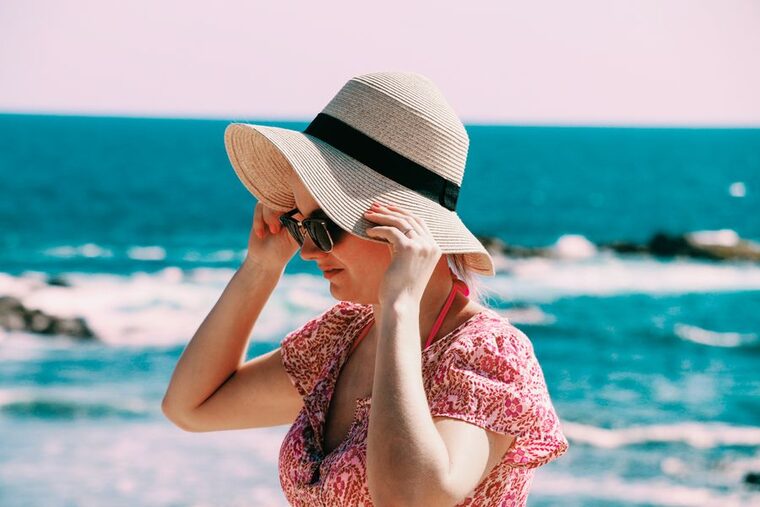 Mulher usando chapéu e óculos escuros para se proteger do sol
